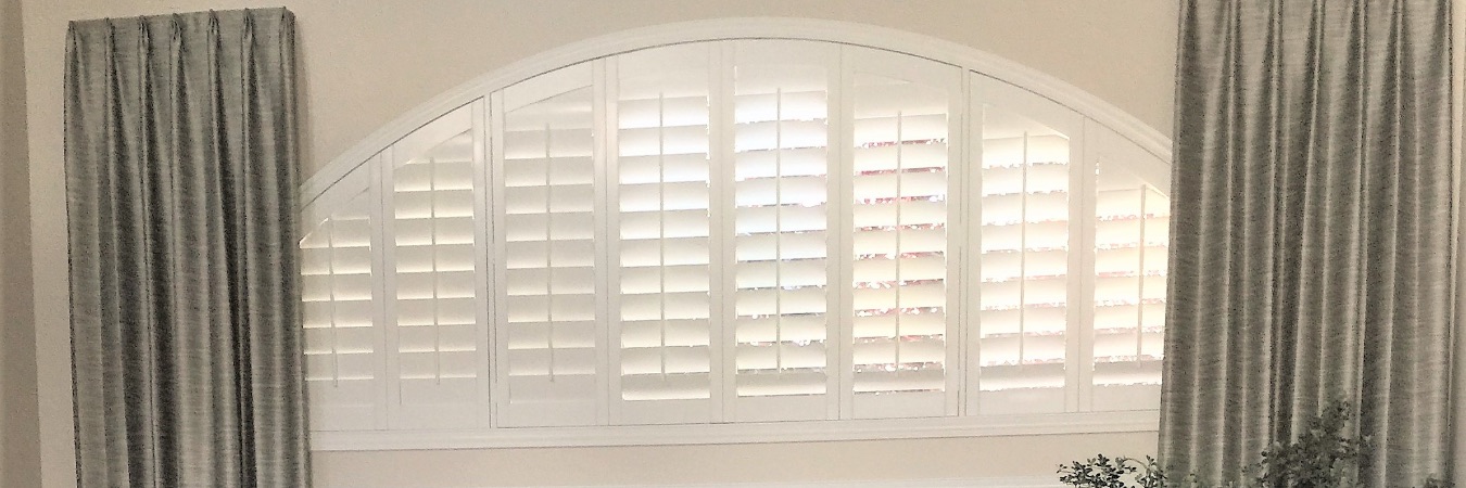 White Polywood shutters on a large arched living room window
